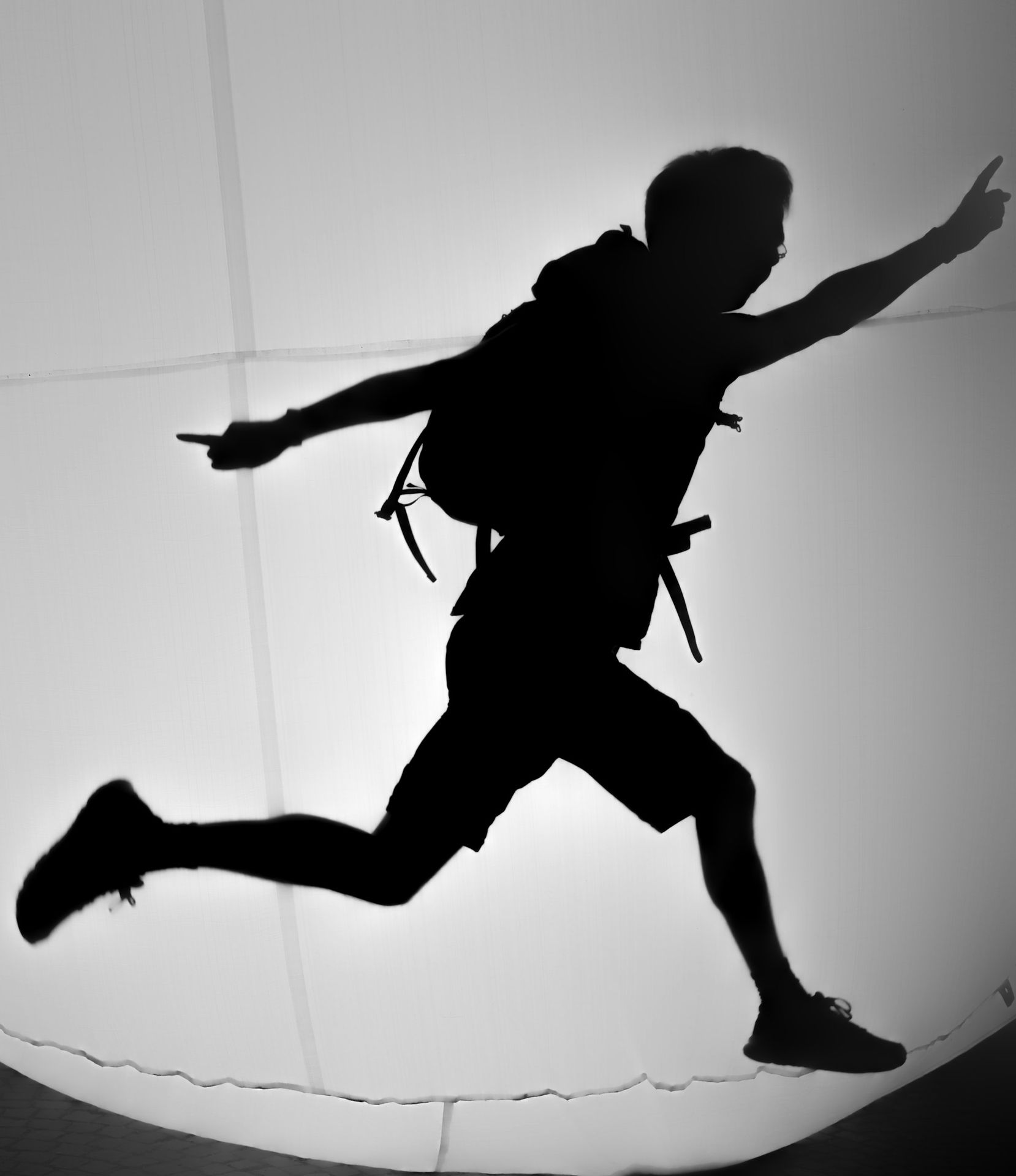 Silhouette of a person jumping with a backpack.